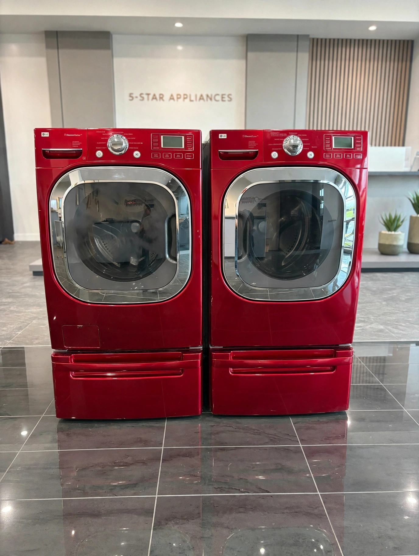 Matching red LG front-load washer and dryer set on a clean showroom floor