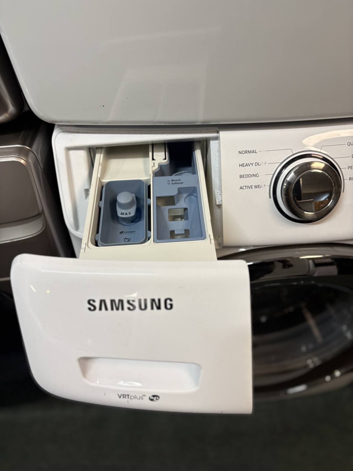 Samsung washer detergent drawer open, showing the detergent, bleach and softener compartments